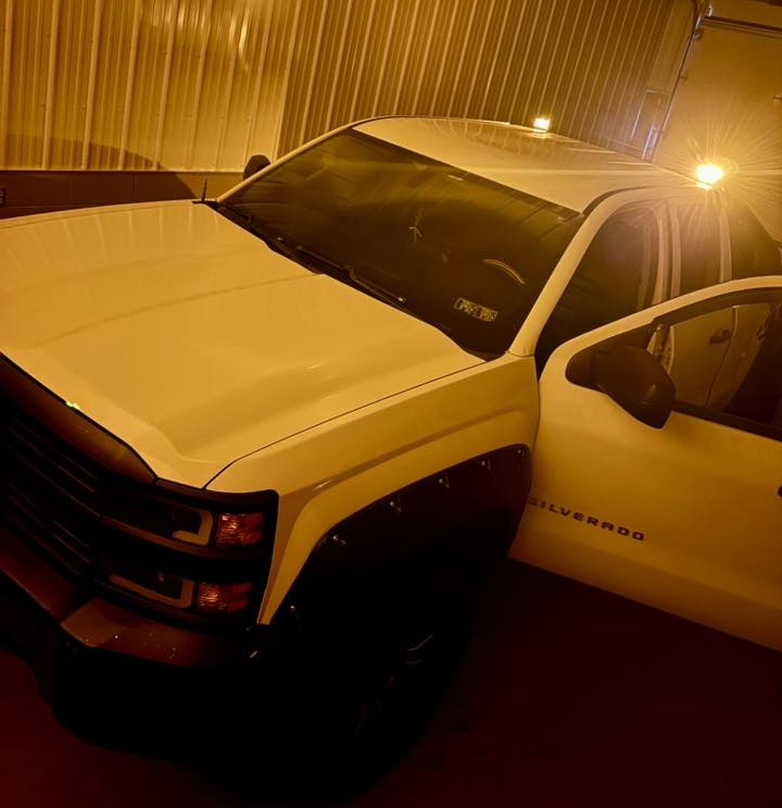 White Chevy Silverado fleet pickup parked inside a shop bay